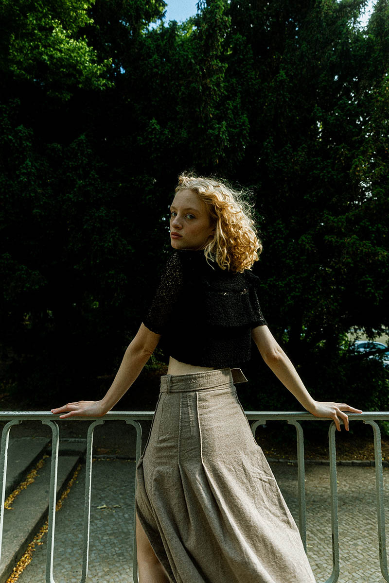 woman leaning against a fence, looking over her shoulder