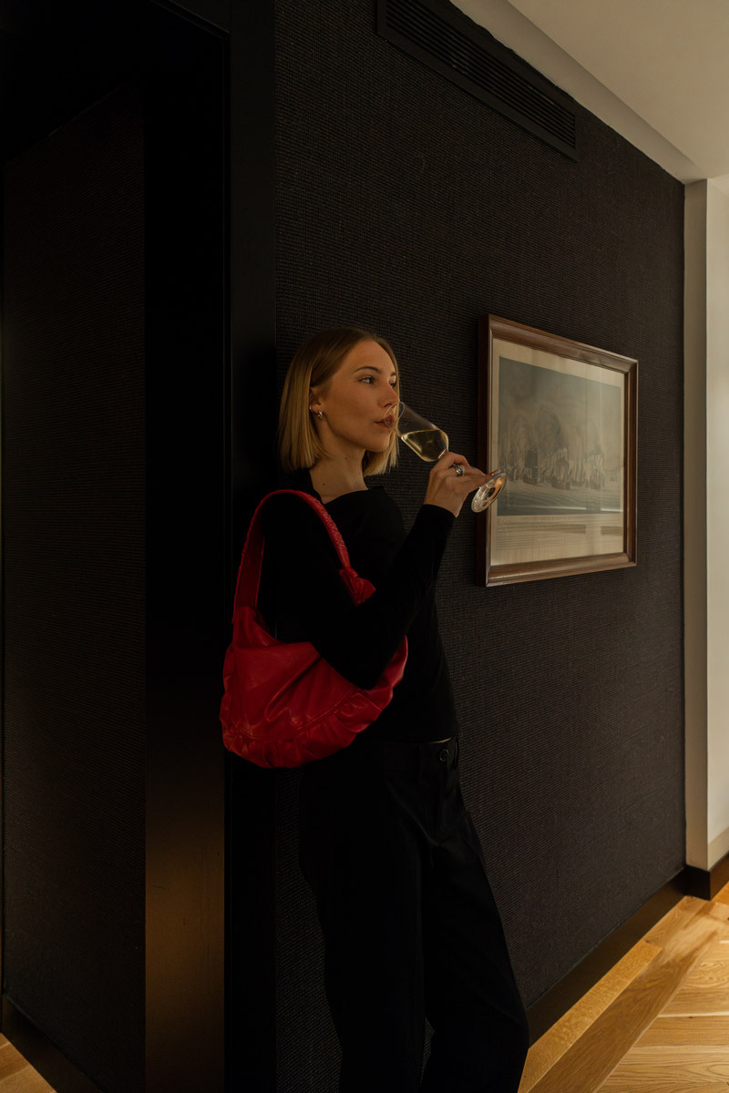woman drinking cava, leaning against a wall