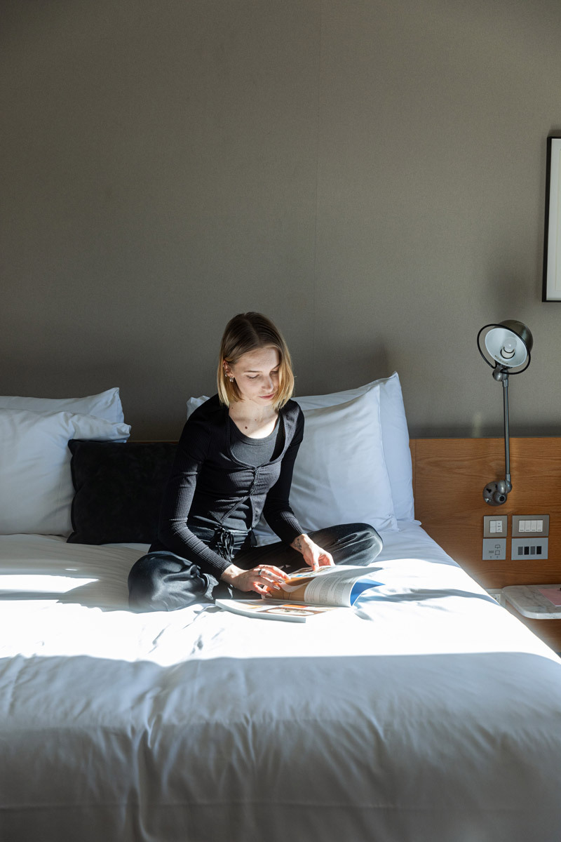 woman reading a magazine, sitting on a bed